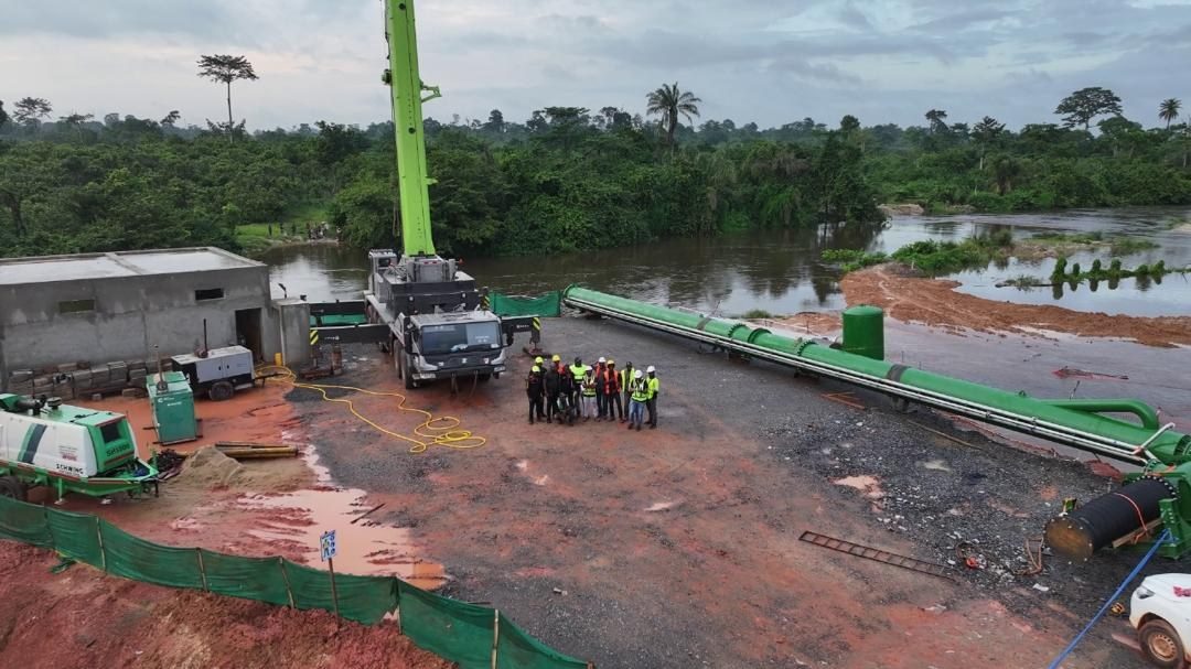 Vue aérienne du chantier — grue et canalisation vers la rivière